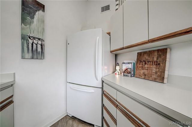 kitchen featuring white refrigerator, white cabinetry, and light hardwood / wood-style flooring