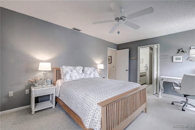 carpeted bedroom featuring a textured ceiling, ensuite bathroom, and ceiling fan