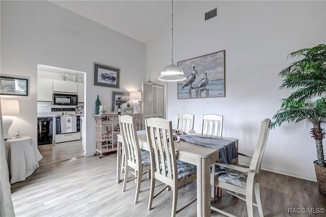 dining space featuring a towering ceiling and light wood-type flooring