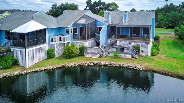 back of house featuring a lawn, a sunroom, and a deck with water view