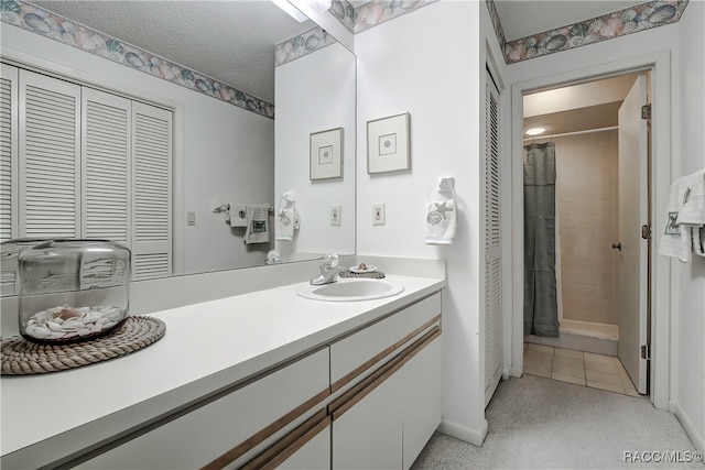 bathroom with vanity, a shower with curtain, a textured ceiling, and tile patterned flooring