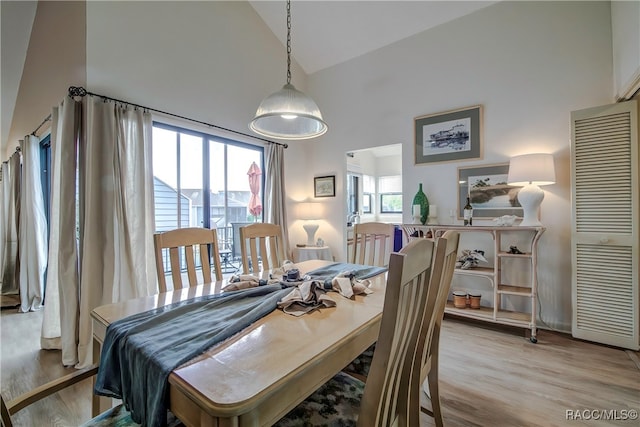 dining area featuring high vaulted ceiling and light hardwood / wood-style floors