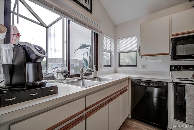 kitchen with white cabinetry, sink, vaulted ceiling, black appliances, and hardwood / wood-style flooring