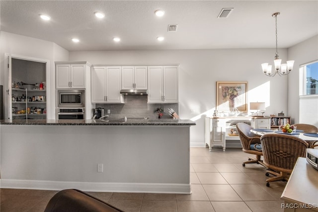 kitchen featuring light tile patterned flooring, backsplash, dark stone countertops, white cabinets, and appliances with stainless steel finishes