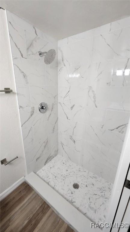 bathroom with hardwood / wood-style floors and a tile shower