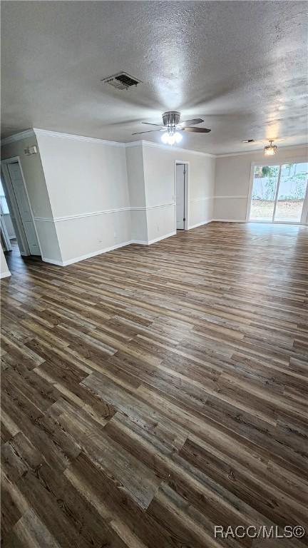 unfurnished living room featuring a textured ceiling, dark hardwood / wood-style flooring, ceiling fan, and crown molding