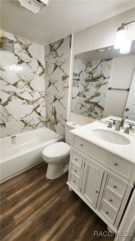 full bathroom with vanity, wood-type flooring, a textured ceiling, and toilet