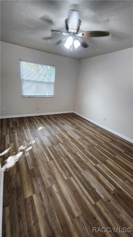 empty room featuring dark hardwood / wood-style floors, ceiling fan, and a textured ceiling