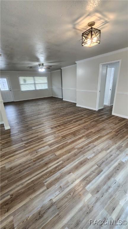 unfurnished living room featuring ceiling fan, wood-type flooring, and ornamental molding