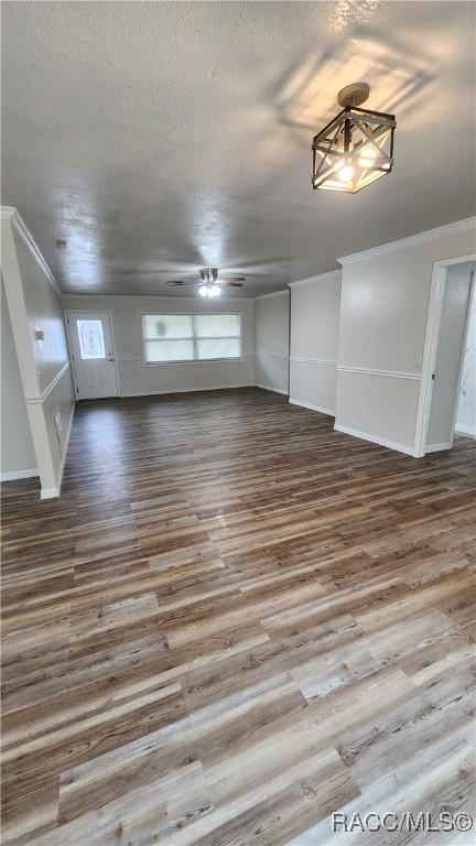 unfurnished living room featuring hardwood / wood-style flooring, ceiling fan, and crown molding