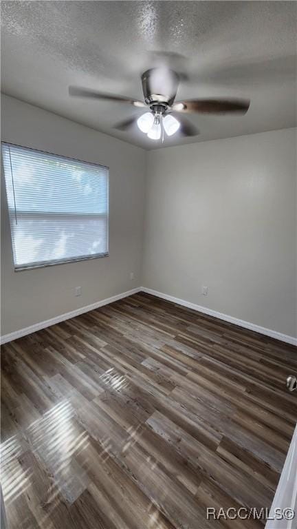 spare room featuring ceiling fan, dark wood-type flooring, and a textured ceiling