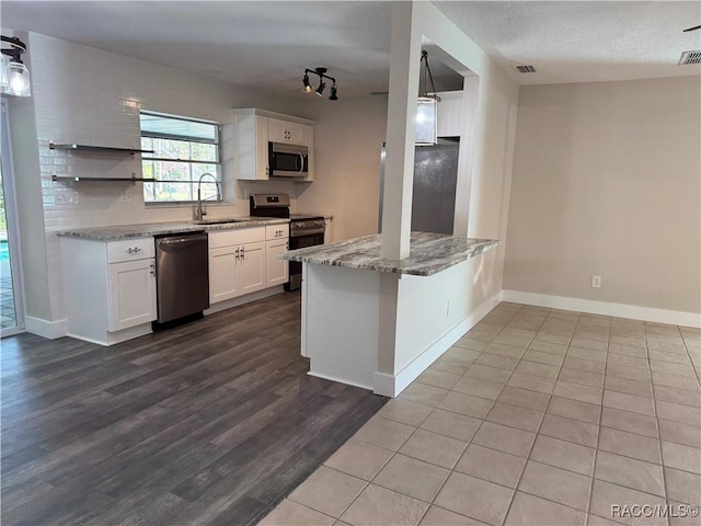 kitchen with appliances with stainless steel finishes, light stone countertops, white cabinetry, open shelves, and a sink