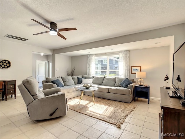 living room with ceiling fan, a textured ceiling, and light tile patterned floors