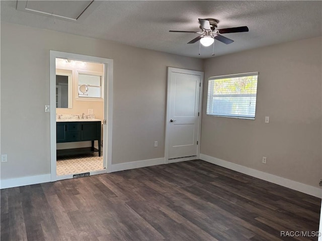 unfurnished bedroom with a textured ceiling, dark wood finished floors, and baseboards