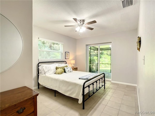 bedroom with ceiling fan, access to exterior, and a textured ceiling