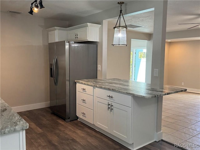 kitchen with stainless steel fridge with ice dispenser, visible vents, white cabinets, light stone countertops, and baseboards