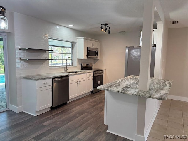 kitchen featuring light stone counters, a sink, white cabinets, appliances with stainless steel finishes, and tasteful backsplash