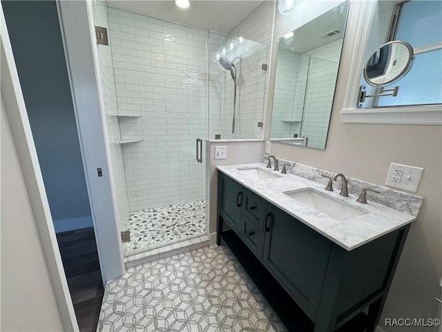 bathroom featuring double vanity, a shower stall, visible vents, and a sink