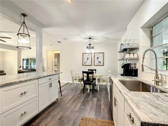 kitchen with light stone countertops, a sink, decorative light fixtures, and white cabinets