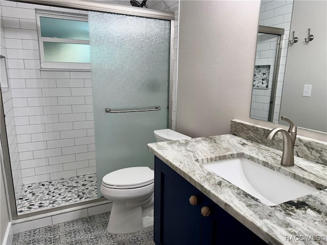 bathroom with vanity, a shower with shower door, and toilet