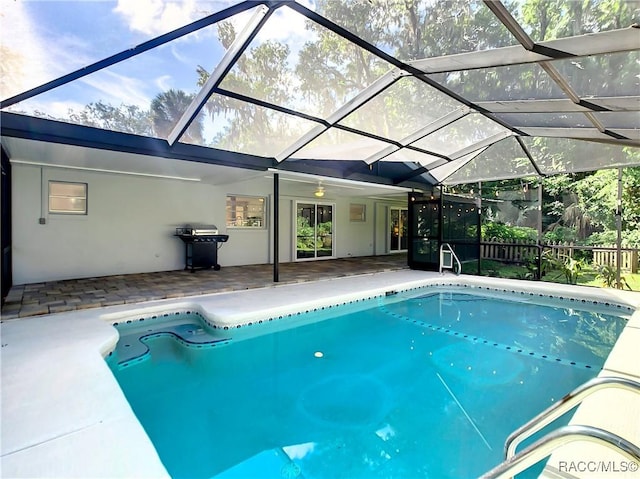 view of swimming pool featuring a grill, glass enclosure, and a patio area