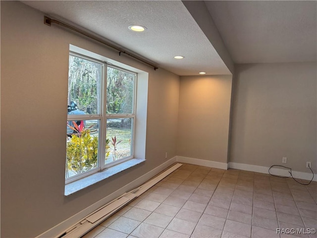 empty room featuring a healthy amount of sunlight, baseboards, and a textured ceiling