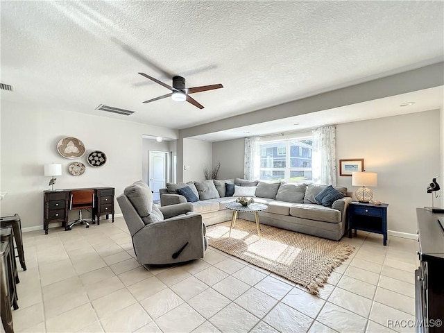 living room with ceiling fan, a textured ceiling, and light tile patterned floors