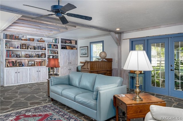 living room with a wainscoted wall, ceiling fan, stone floors, french doors, and beam ceiling