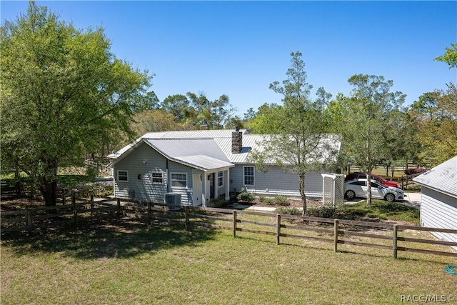 ranch-style house with a fenced front yard, a chimney, metal roof, and a front yard