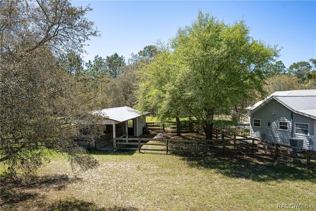 view of yard with a rural view, fence, and central AC