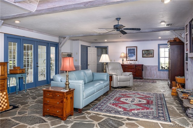 living room featuring a wainscoted wall, stone floors, visible vents, and french doors