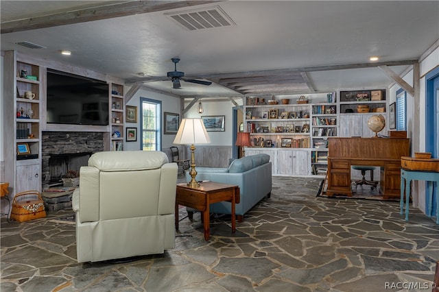 living area featuring built in features, stone flooring, visible vents, and a fireplace