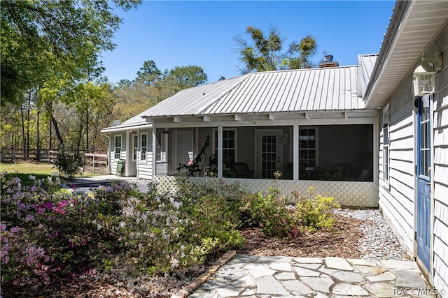 rear view of property featuring metal roof, fence, and a sunroom