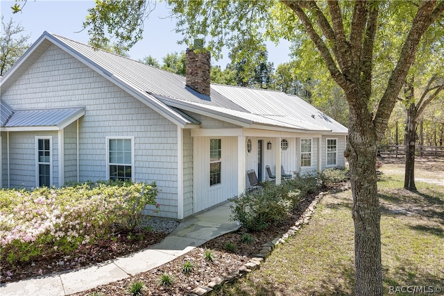 ranch-style house featuring metal roof and a chimney