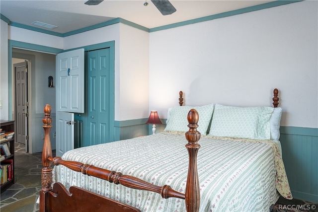 bedroom with visible vents, wainscoting, ceiling fan, crown molding, and a closet