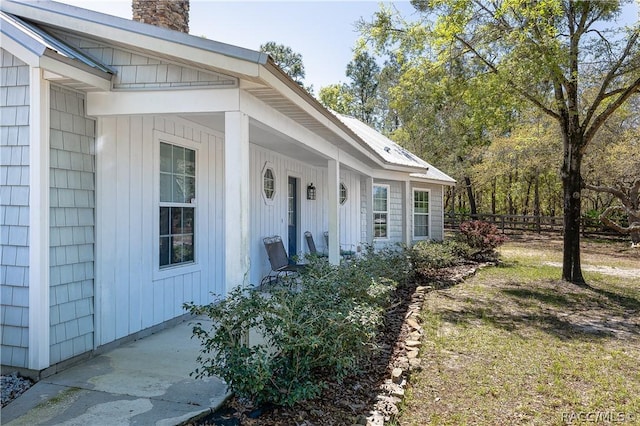 doorway to property featuring a chimney and fence