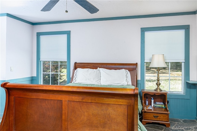 bedroom with ceiling fan and wainscoting