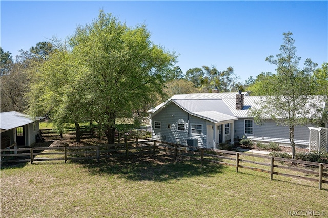 exterior space featuring a fenced front yard, a chimney, a front lawn, and metal roof