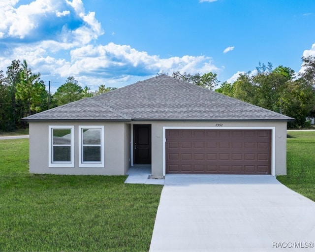 ranch-style home with roof with shingles, an attached garage, driveway, and a front lawn