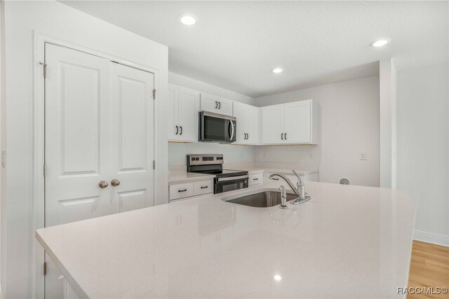 784 E Alaska Ln, Hernando, FL 34442 - kitchen with appliances with stainless steel finishes, white cabinets, recessed lighting, a kitchen island with sink, and light wood finished floors
