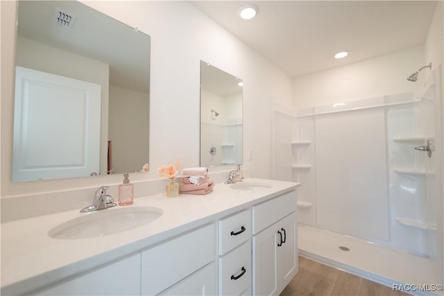 full bathroom featuring a shower, double vanity, a sink, and visible vents