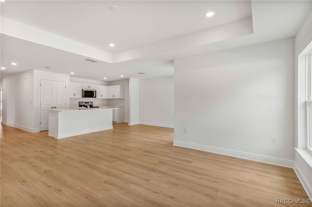 784 E Alaska Ln, Hernando, FL 34442 - unfurnished living room with recessed lighting, light wood-style flooring, and a tray ceiling