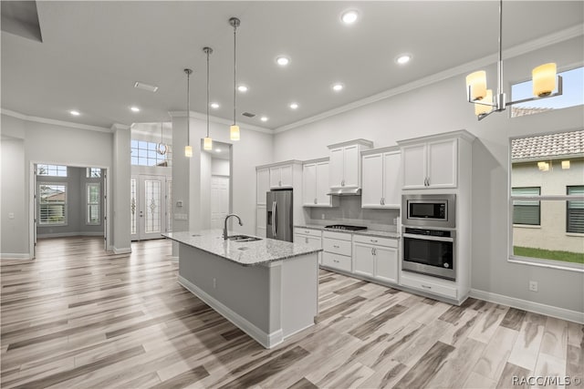 kitchen featuring a center island with sink, white cabinets, pendant lighting, and appliances with stainless steel finishes