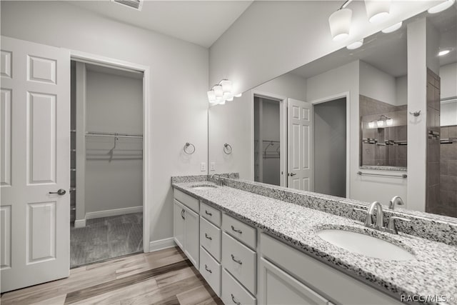 bathroom featuring tiled shower, hardwood / wood-style floors, and vanity