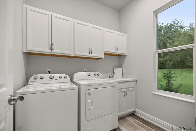 laundry area featuring washer and dryer, sink, cabinets, and light wood-type flooring