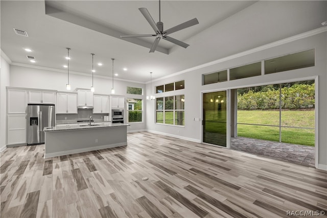 kitchen with a kitchen island with sink, sink, light wood-type flooring, appliances with stainless steel finishes, and white cabinetry