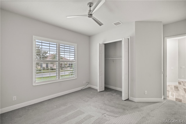 unfurnished bedroom featuring a closet, light colored carpet, and ceiling fan