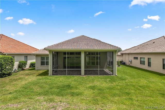 rear view of house featuring a sunroom and a lawn