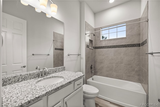 full bathroom with vanity, hardwood / wood-style floors, tiled shower / bath combo, and toilet