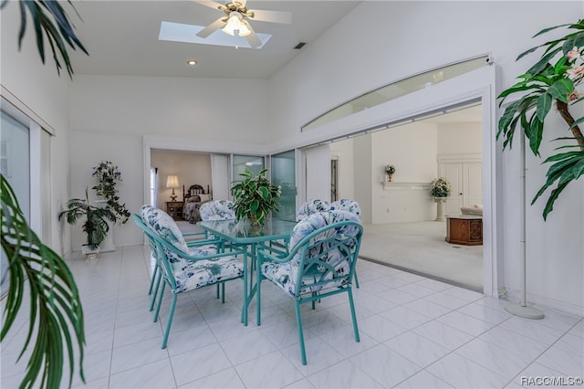 carpeted dining space with lofted ceiling with skylight and ceiling fan